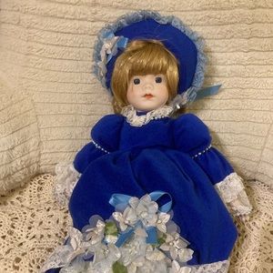 Vintage Porcelain Doll with Blue Coat, Bonnet, and Floral Appliqué Detail